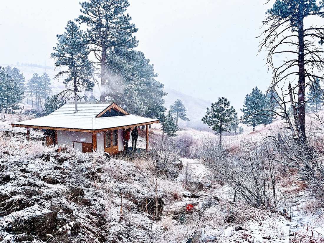 Snow falling on the teahouse, woodsmoke rising, figures on the porch