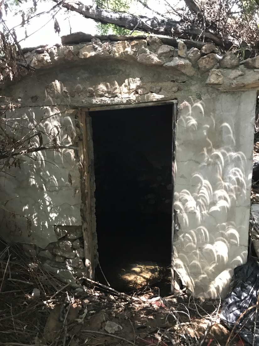 The historic stone and plaster springhouse ruin in dappled light