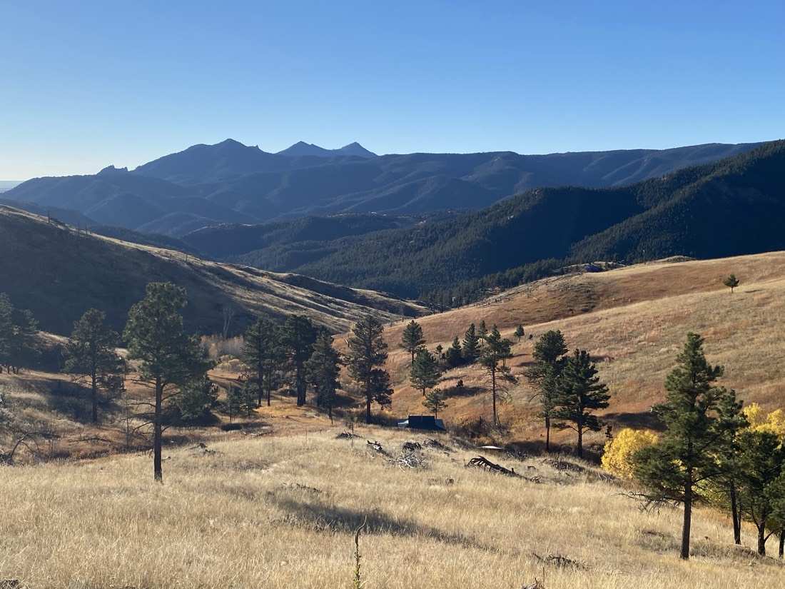Autumn view across the ranch valley to the peaks, meadows and pine stands below