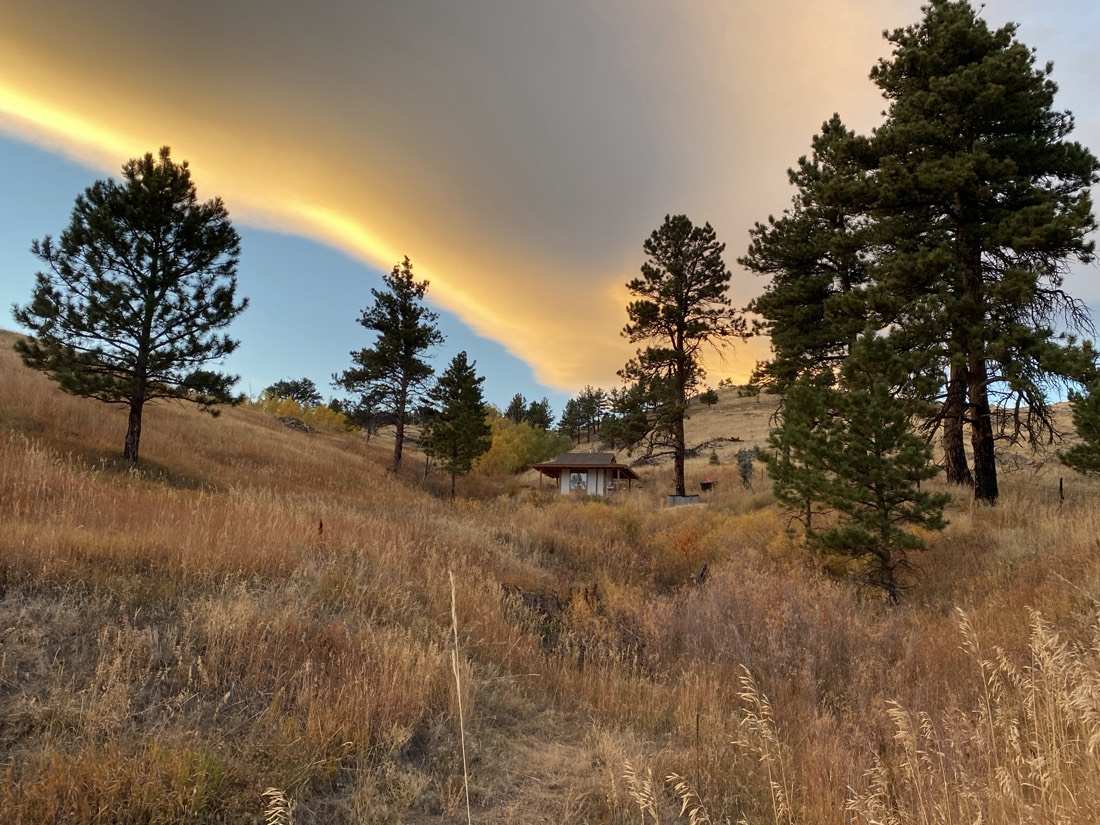 A golden sunset cloud band over the pines, the teahouse small in the draw