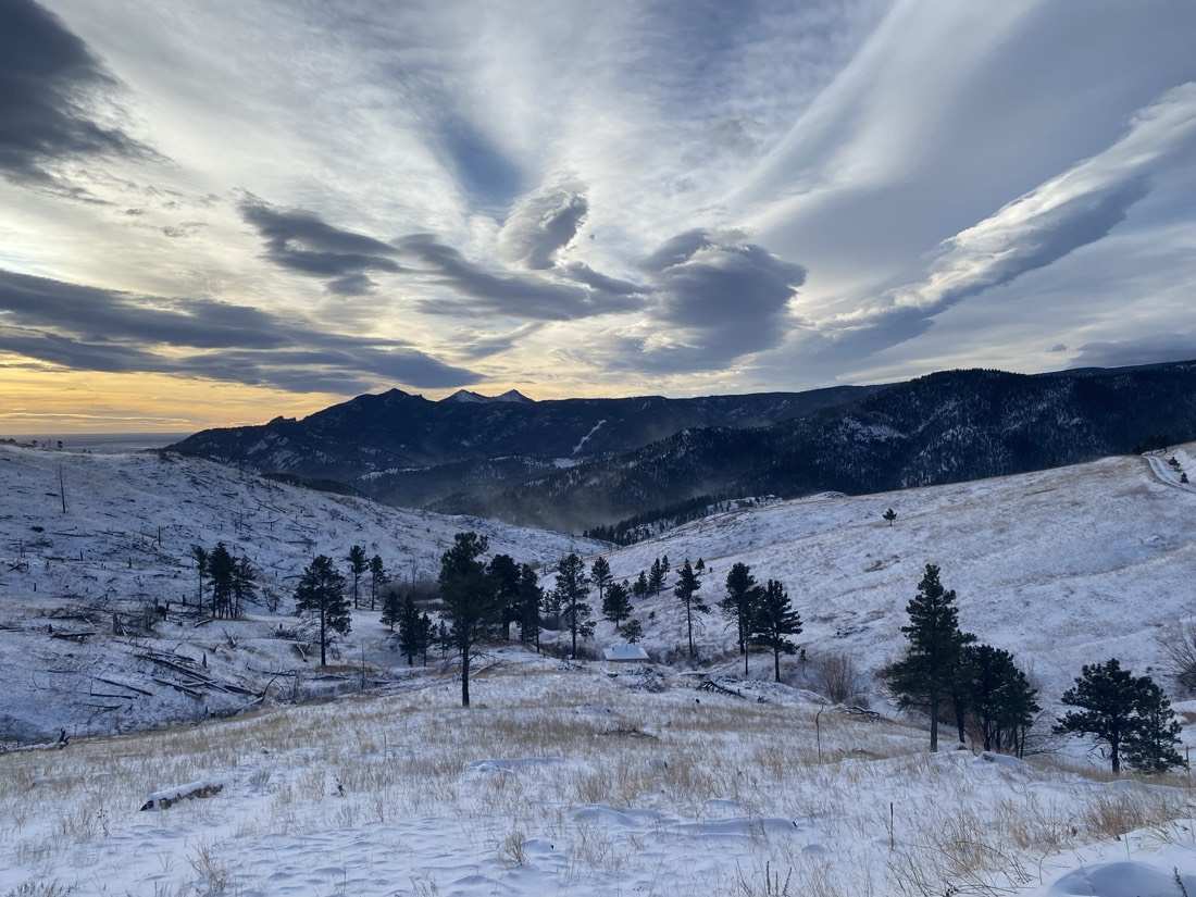 Winter dusk: lenticular clouds over the snowy valley and dark peaks