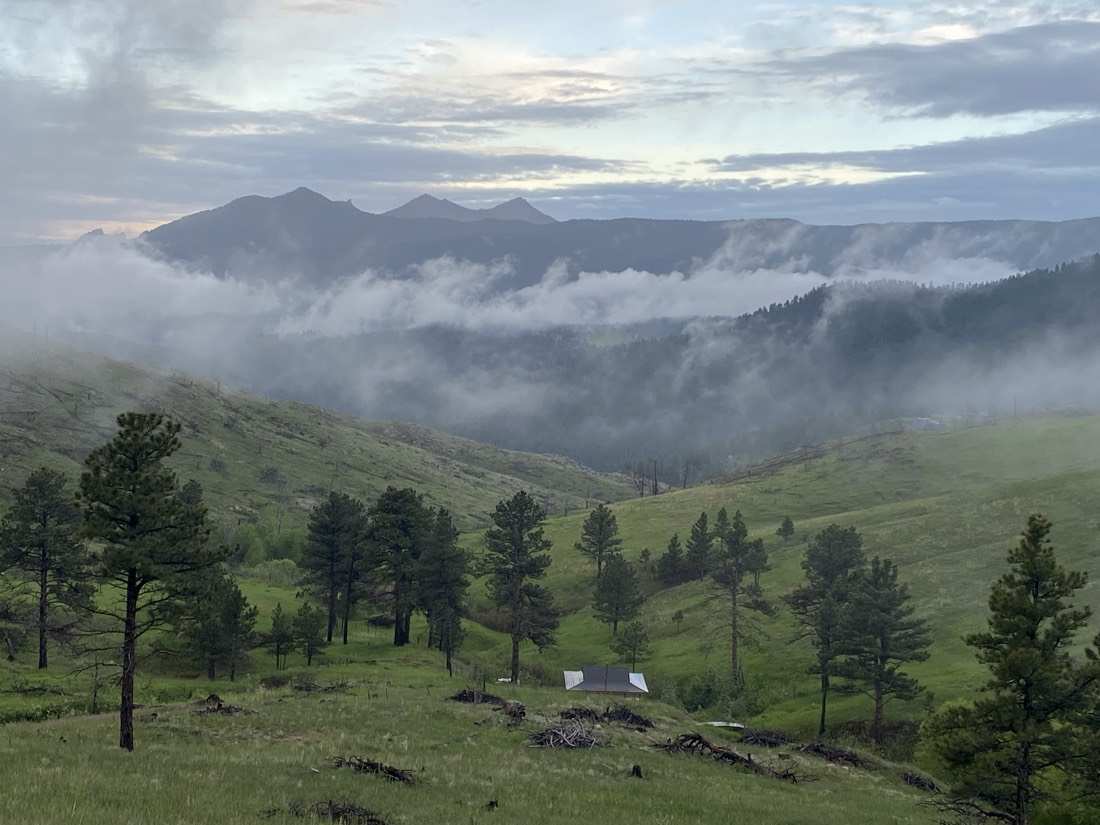 Morning fog rolling through the green valley below the ranch, peaks on the skyline