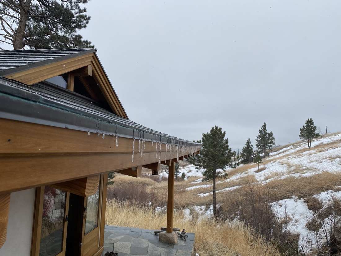 Icicles along the teahouse eave, copper edge and snowy hillside beyond