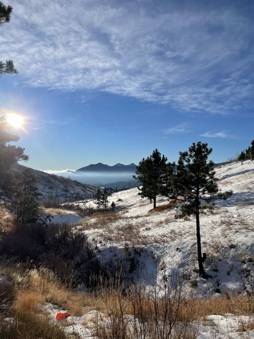 Winter sun over snowy slopes with a cloud inversion below the peaks