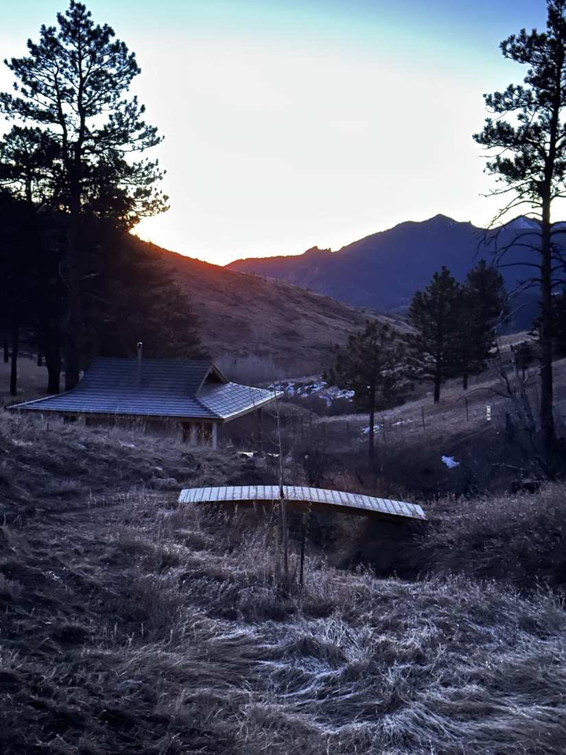 The teahouse and footbridge at dusk, sun cresting the ridge